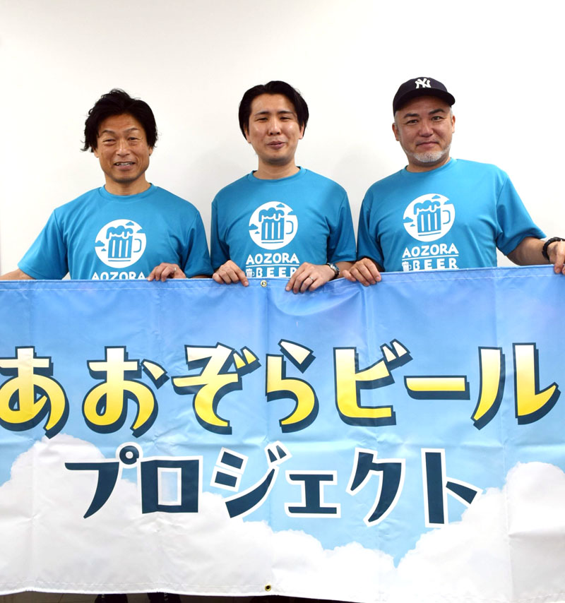 森沢さんのエッセー集をイメージした「リアルあおぞらビール」をPRする山崎さん(左端)ら=船橋市役所